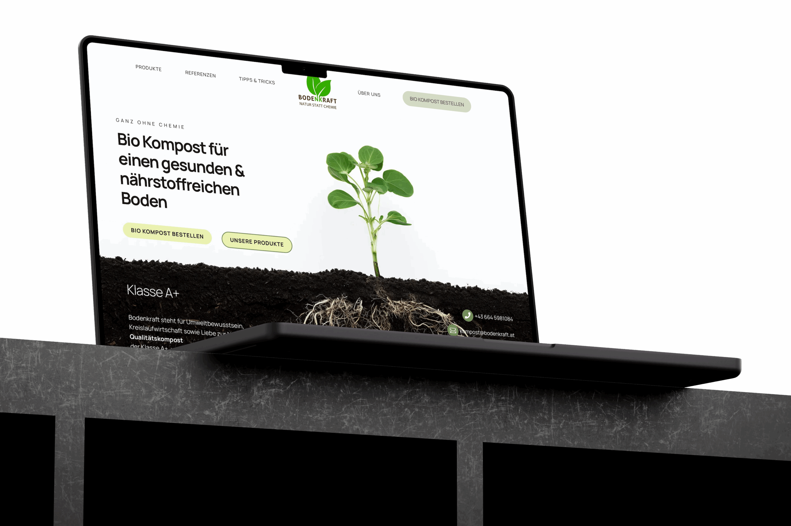 Macbook auf einem Steinsockel zeigt die Webseite bodenkraft.at